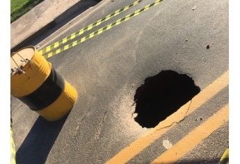 Buraco superficial esconde perigo, com cratera escavada pelas águas, na marginal que liga o trevo da UnIFAI à Avenida XV de Novembro (Foto: Siga Mais).