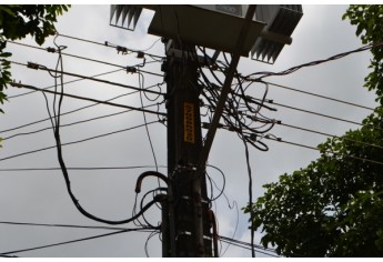 Cabos de baixa tensão de um ramal de unidade consumidora foram desconectados pelo cliente e deixados pendurados ao poste, no centro de Adamantina (Foto: Acácio Rocha).