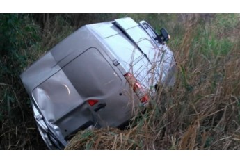 Van ficou parcialmente tombada após a colisão e invadir área de vegetação (Foto: Cedida/PM Rodoviária).