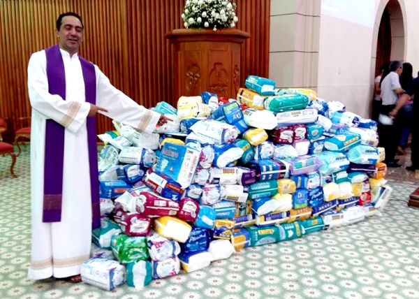 Padre Rui, pároco da Igreja Matriz de Santo Antônio, e as fraldas geriátricas arrecadadas pela comunidade, e que agora ajudarão pessoas que precisam desses materiais (Foto: No Click do Senhor).
