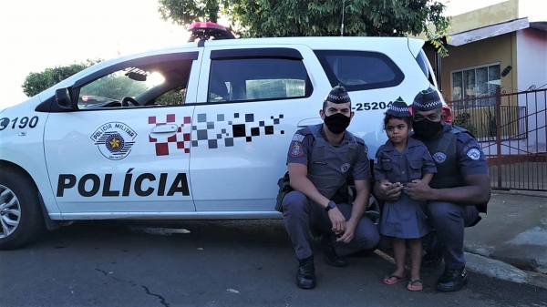 Sonho realizado: a pequena Rebeca junto a dois policiais, já vestindo o fardamento que ganhou de presente (Divulgação/PM).