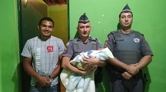 Policias militares cabo Rezende e soldado Domingues, do efetivo da PM de Lucélia, com o pai e a criança salva com o emprego da manobra de Heimlich (Foto: Cedida/PM).