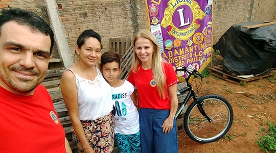 Companheiros Sival e Eliane realizando a entrega da bicicleta para o aluno Lucas da Silva Garcia juntamente com sua mãe Rosana (Assessoria de Imprensa).