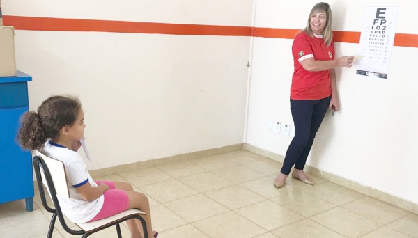 Carmem Bettio realizando exame de acuidade visual nas crianças atendidas pela Casa do Garoto (Foto: Assessoria de Imprensa/Lions Clube de Adamantina).