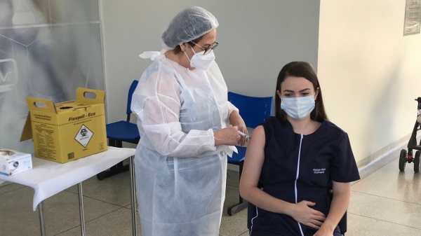A auxiliar de enfermagem Geny Maia aplica a primeira dose da Coronavac na enfermeira Daiane Stefani Périco (Foto: Siga Mais).