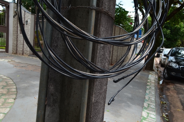 Cabos de baixa tensão de um ramal de unidade consumidora foram desconectados pelo cliente e deixados pendurados ao poste, no centro de Adamantina (Foto: Acácio Rocha).