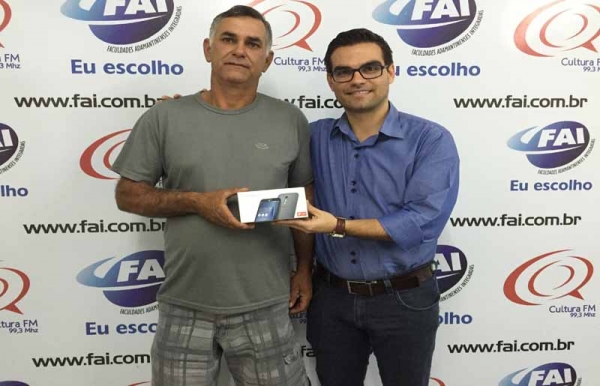 Fotografia: Legenda: Vanoir recebe o aparelho de Fabrício Lopes, representando o diretor geral, prof. Dr. Márcio Cardim (Foto: Tiago Sichieri/Agência FAI)