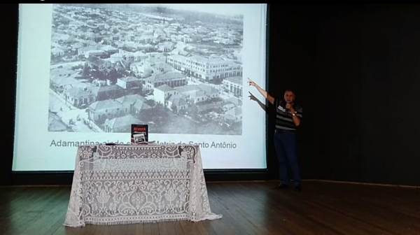 Em uma palestra, no lançamento, João Carlos Rodrigues mostra uma foto da área central da cidade, na década de 50, sem a Igreja Matriz de Santo Antônio (Reprodução/Clickar).