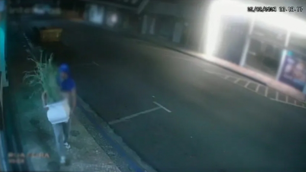 Imagens de monitoramento flagraram a tentativa do homem em quebrar a porta de vidro da loja (Reprodução/AdamantinaNet).