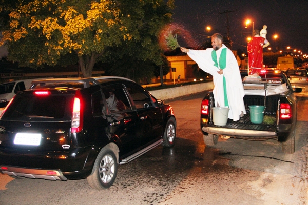 Padre Domingos aspergindo veículo defronte a paróquia