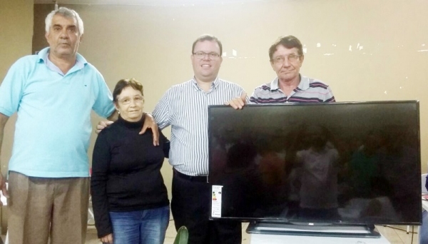 Valdecir, padre Jorge e Mauro Coletti, durante entrega à representante da ganhadora da TV (Foto: Cedida).