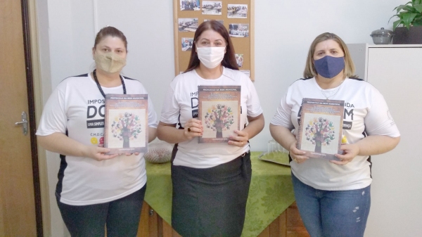 Vice-presidente do CMDCA, Darcy Souza Silva, Secretária de Assistência Social, Andreia Ribeiro e presidente do CMDCA, Érica Grespi Maião, exibem o Protocolo da Escuta Especializada (Assessoria de Imprensa/IR do Bem).