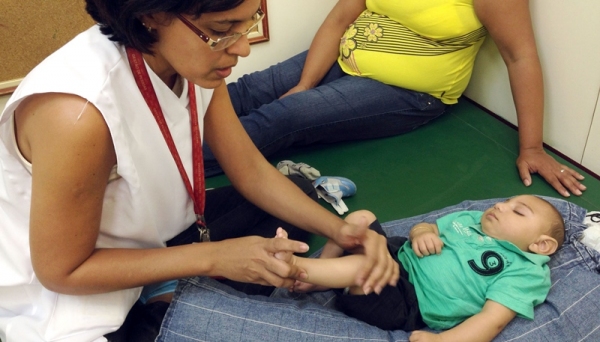 A fisioterapeuta Cynthia Ximenes da Associação de Assistência à Criança Deficiente (Recife/PE) atende bebês com microcefalia e orienta as mães sobre como fazer os exercícios em casa para melhorar o desenvolvimento das crianças (Foto: Sumaia Villela/ Agência Brasil).