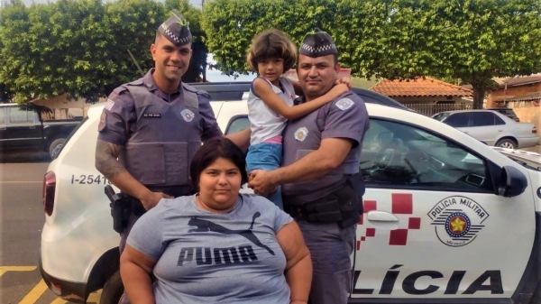 A menina de 7 anos no colo de um dos policiais que atuaram no seu socorro (Divulgação/PM).