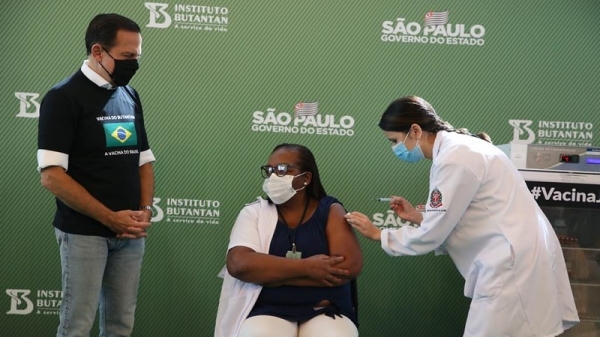 A enfermeira Mônica Calazans recebeu a primeira dose da vacina, aplicada pela também enfermeira Jéssica Pires de Camargo, observadas pelo governador João Dória (GovSP).