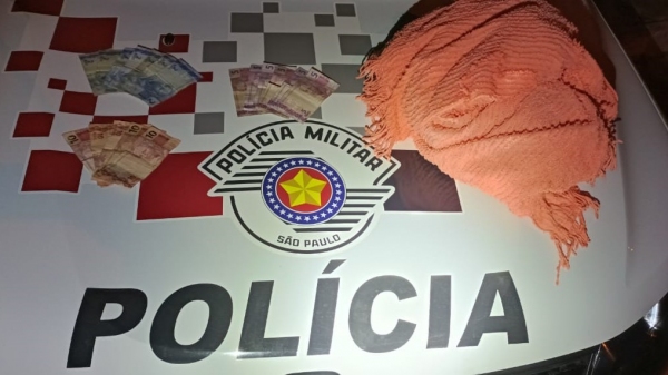 Dinheiro recuperado e a coberta usada pelo criminoso no roubo (Divulgação/PM).
