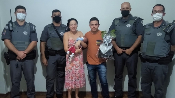 Os policiais militares envolvido no atendimento à família, com os pais da criança e o pequeno Henry (Divulgação/PM).