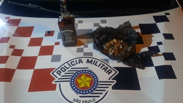 A garrafa de bebida e as moedas que totalizaram R$ 48,70, apreendidas com o trio (Divulgação/PM).