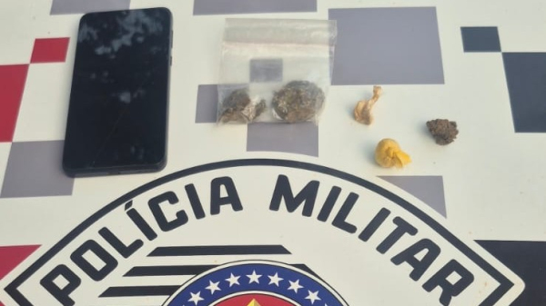 Aparelho celular e drogas apreendidos com o homem de 26 anos (Cedida/PM).
